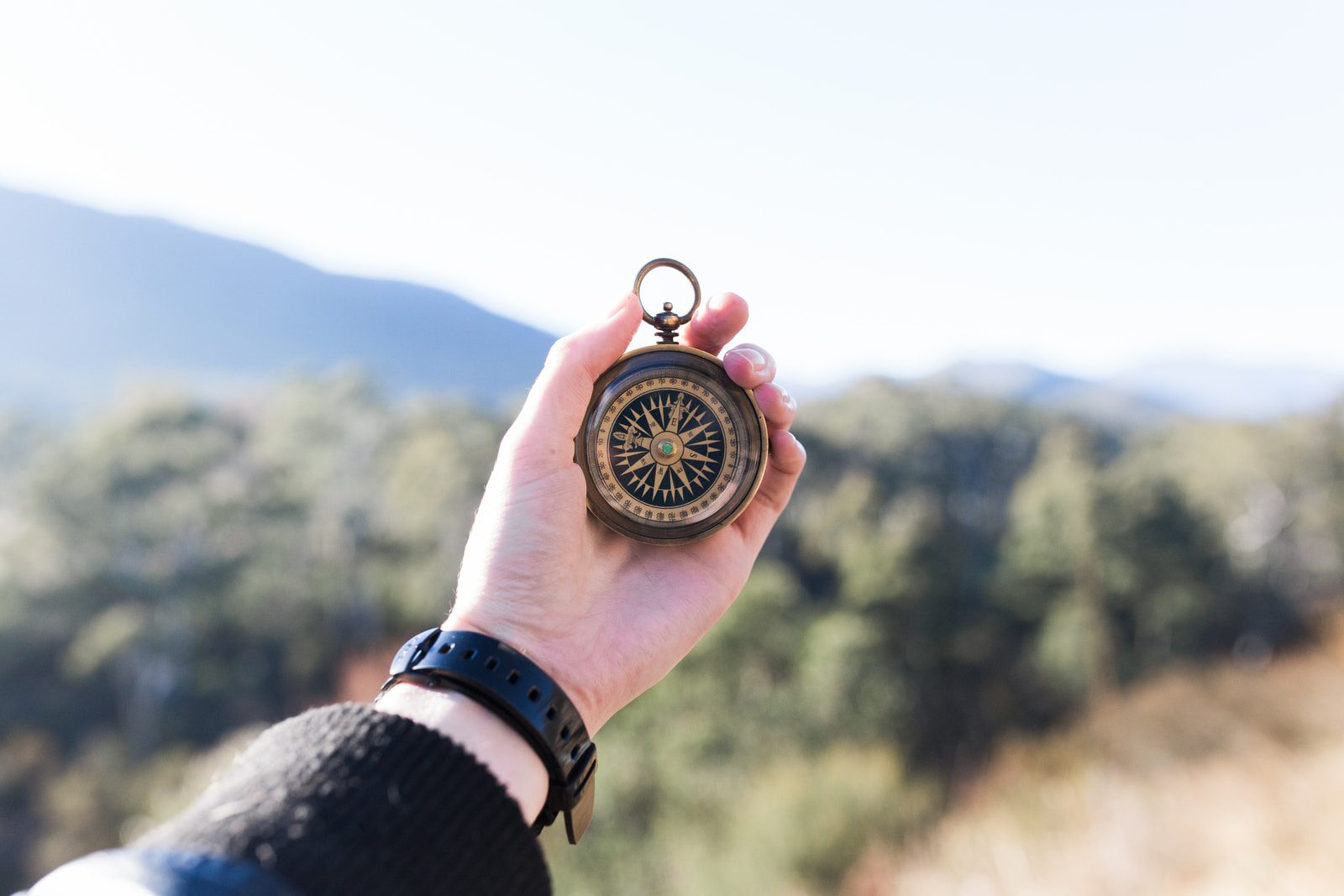 Spiritual Direction vs. Coaching- Photo of a compass held out in front of a mountain vista