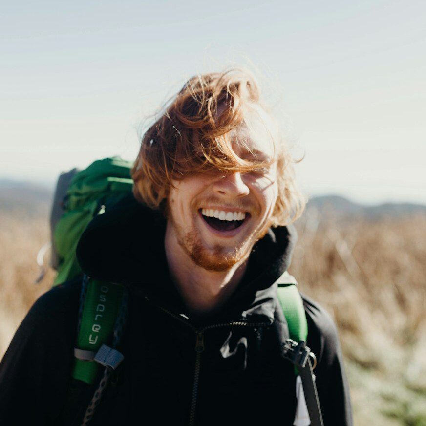 smiling man with green mountaineering bag during daytime