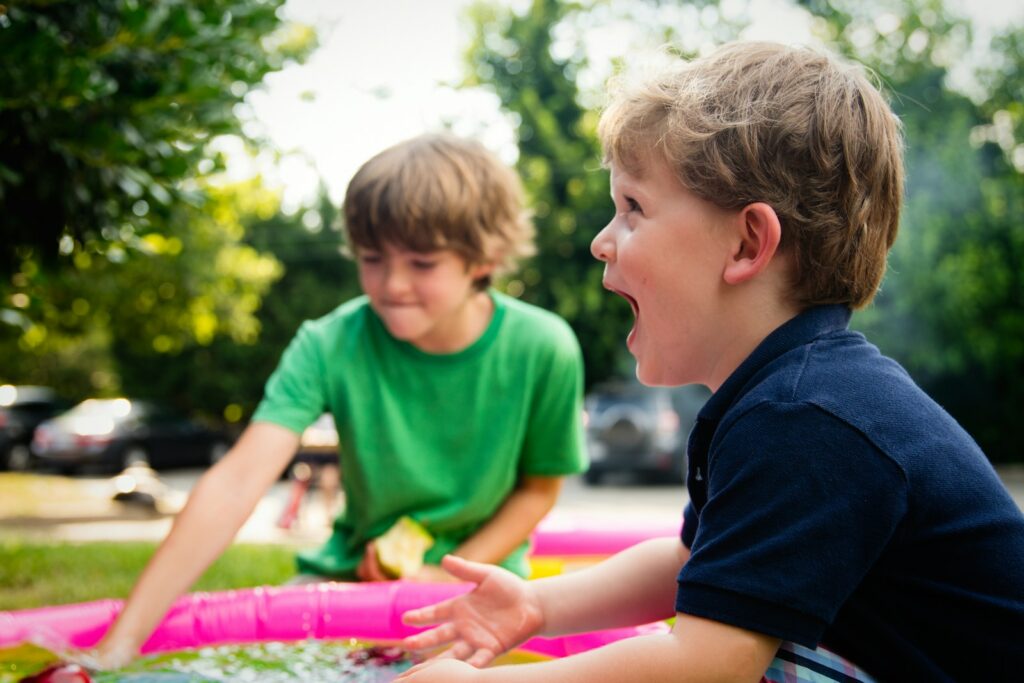 two boys playing outside, one laughing