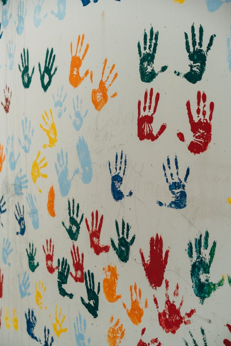 a group of multicolored hand prints on a white wall